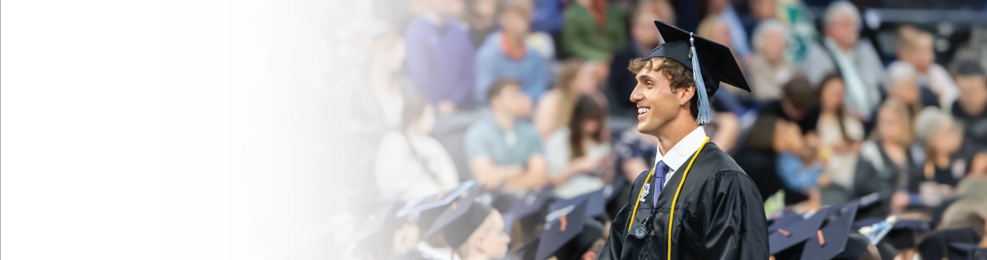 Graduate walking in commencement ceremony, smiling.