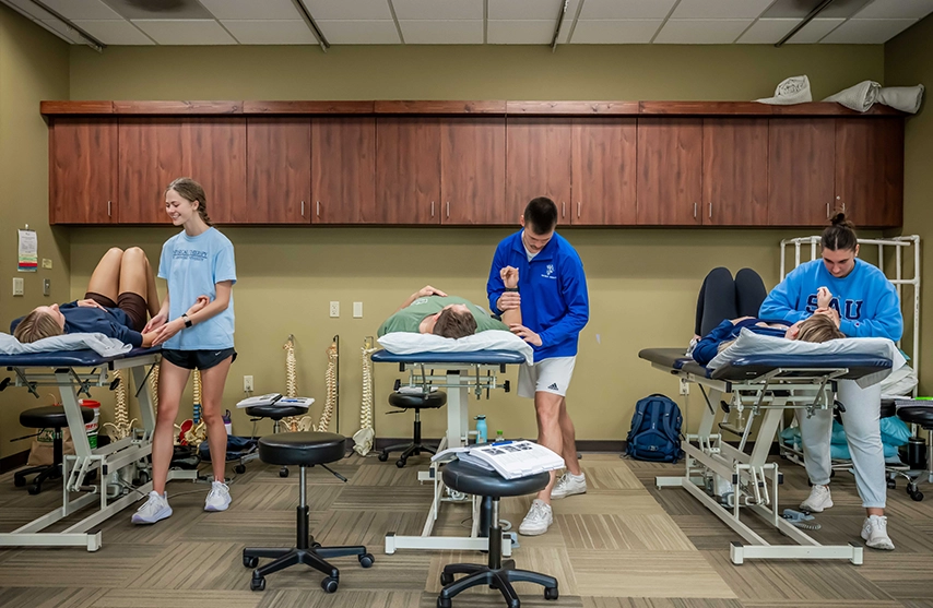 Three students work on PT techniques at St. Ambrose University.