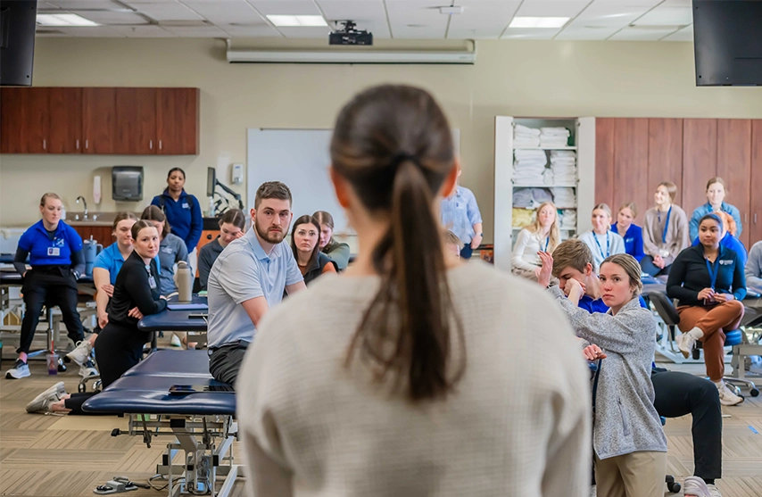 An instructor lectures a group of physical therapy students.