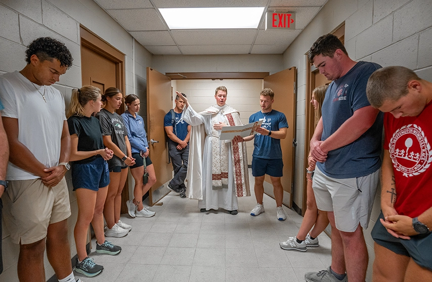Fr. Dale and students stand together as Fr. Dale blesses the anatomy lab.