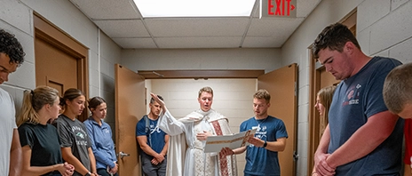 Fr. Dale and students stand together as Fr. Dale blesses the anatomy lab.