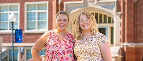 Grace Bickle and Megan McConnaughay stand next to each other and smile at the camera.