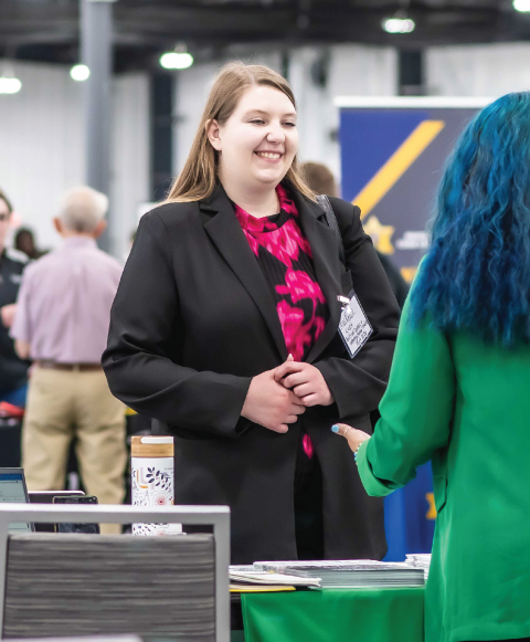 Woman standing at booth at job fair.