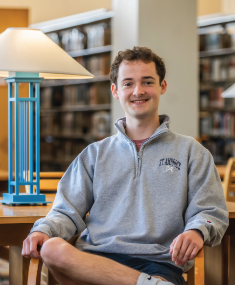 Student smiling in library, seated at table.