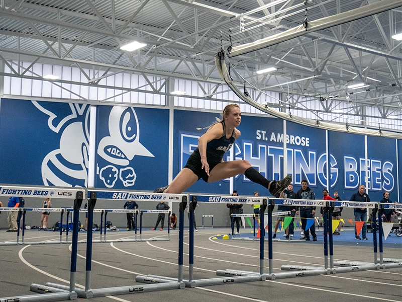 A student leaps over a hurdle during a track meet.