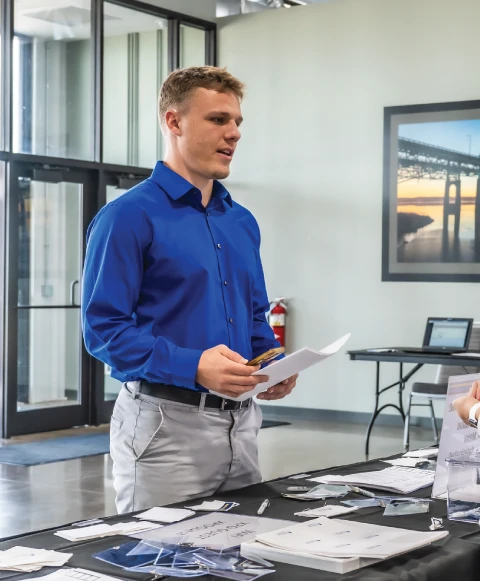 Student standing indoors at a career fair table.