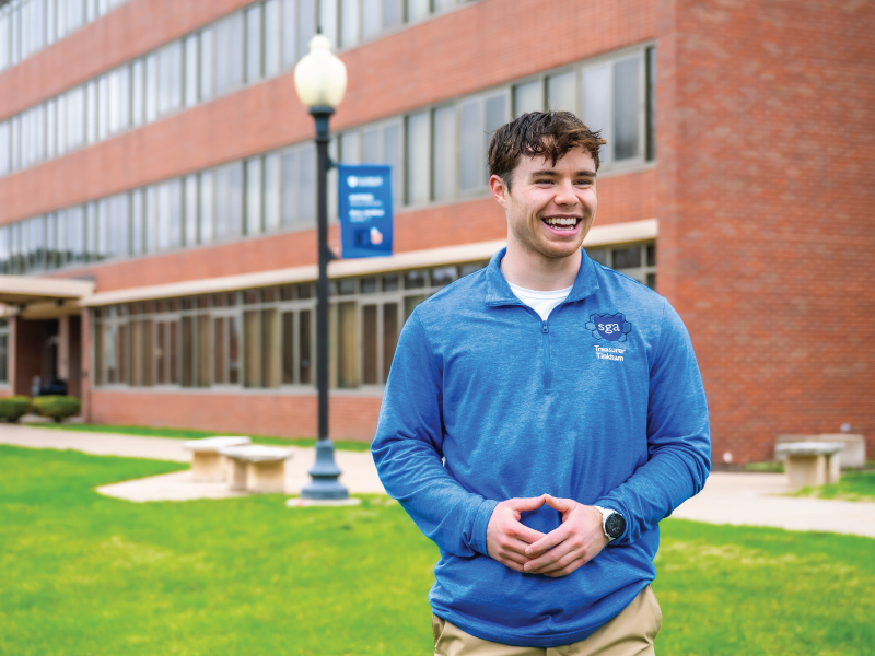 Student outside dorm, smiling broadly.