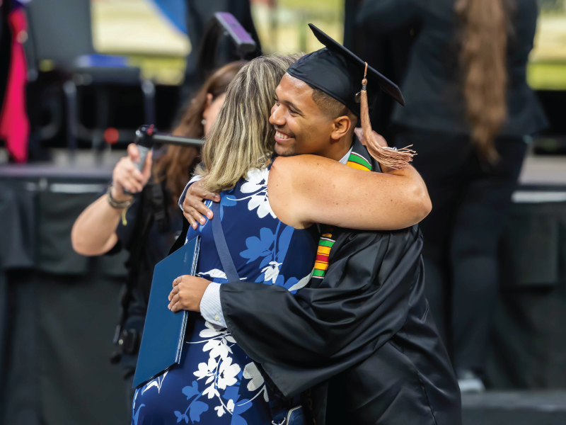 Graduate hugging staff member at commencement.