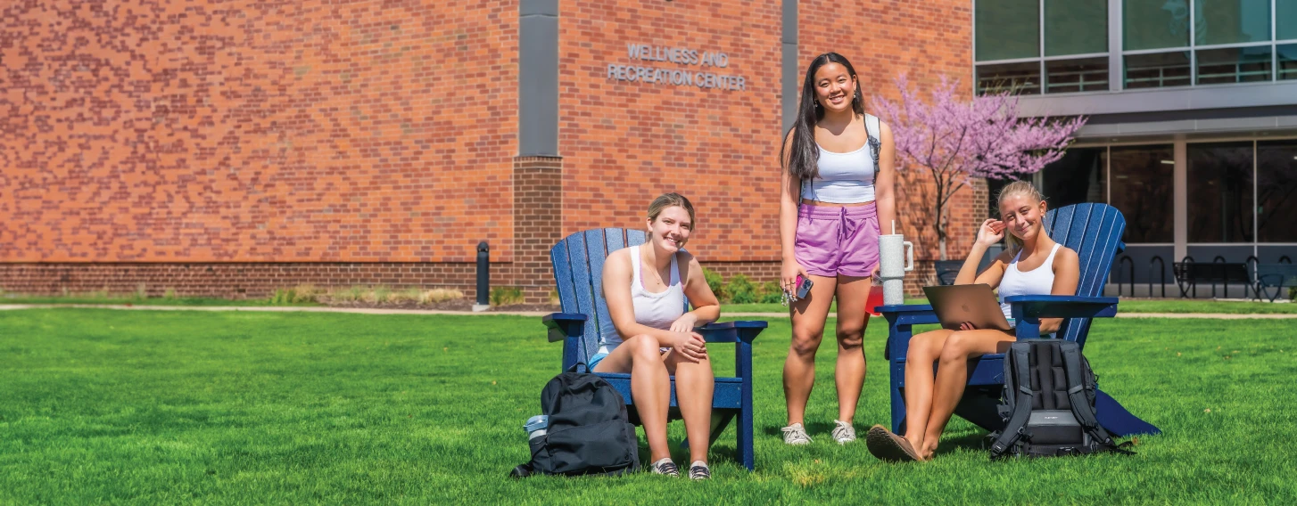 Group of three students on quad on a sunny day.