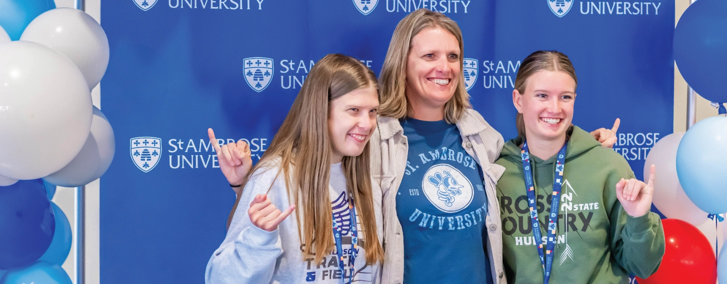 Parent posing with two students against blue SAU background.