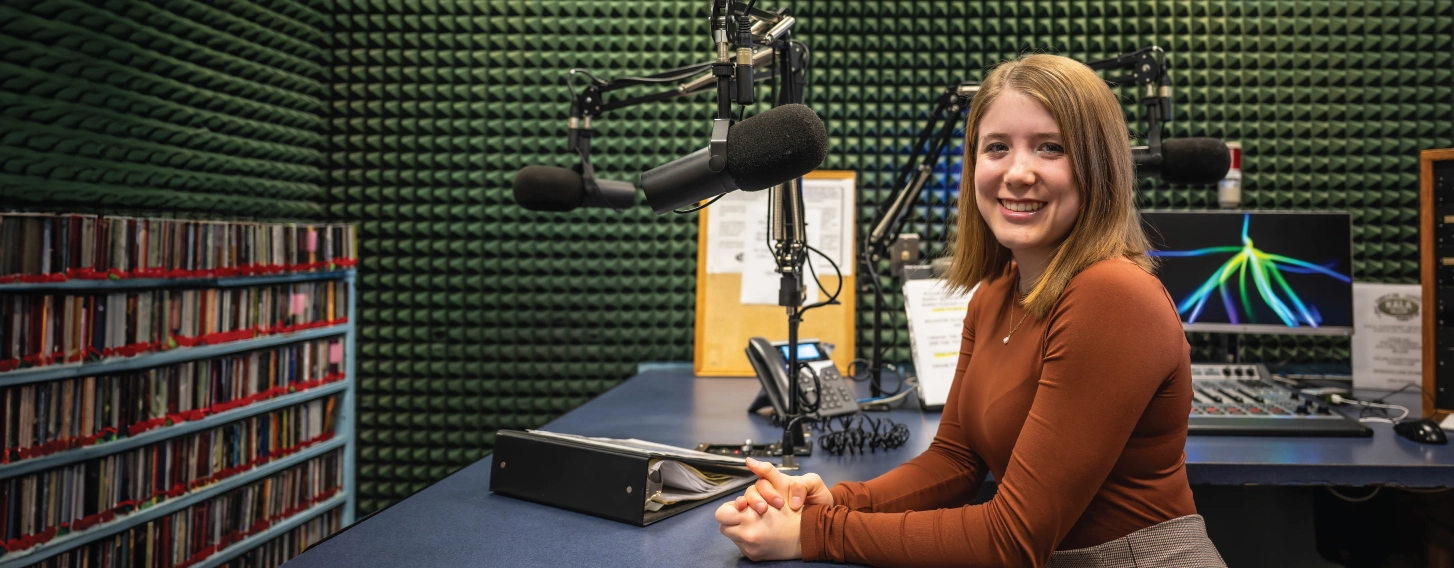 Student broadcasting on radio from booth.