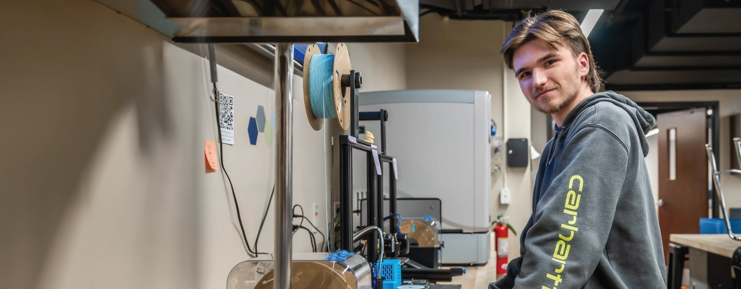 Engineering student next to equipment in lab.