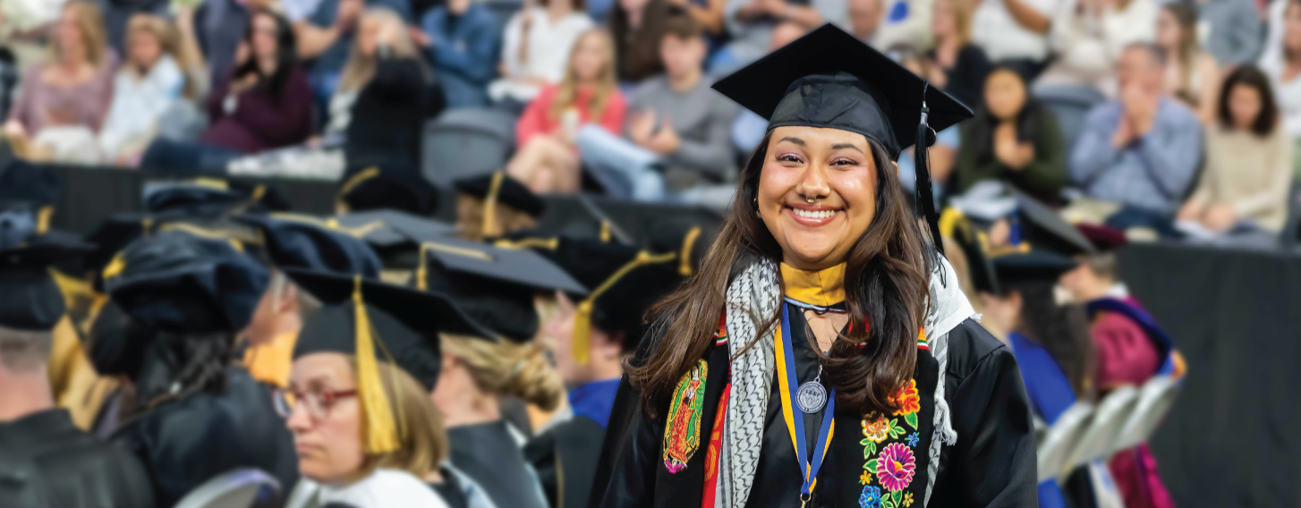 Master degree graduate smiling at commencement.