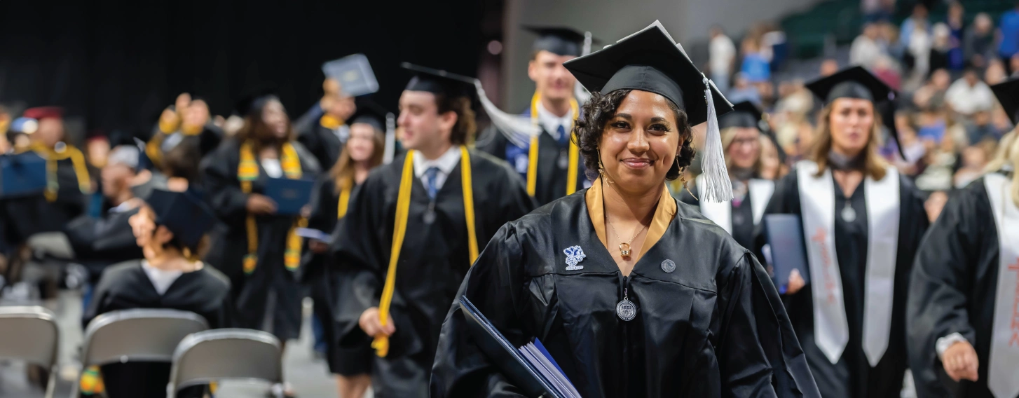 Graduate walking with diploma at graduation.