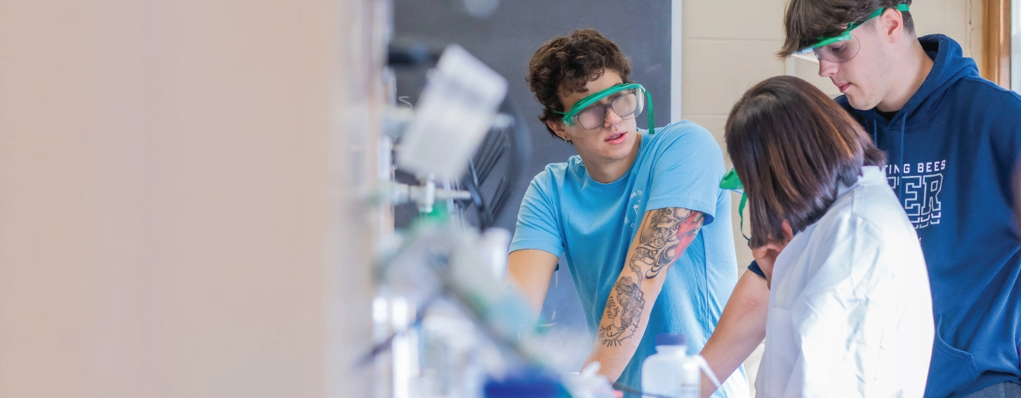 Two people with professor in a chemistry lab conducting experiment.
